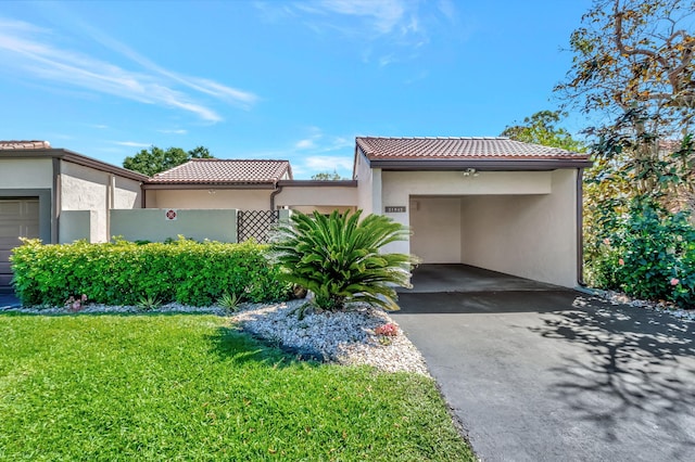 view of front of home with driveway, a tiled roof, a front yard, and stucco siding