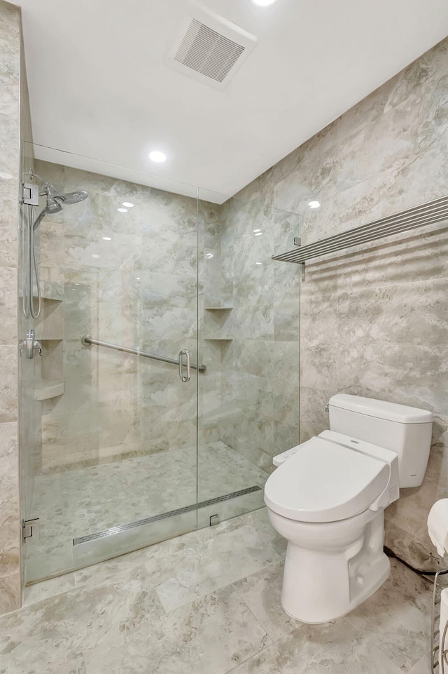 bathroom with toilet, a shower stall, visible vents, and tile walls