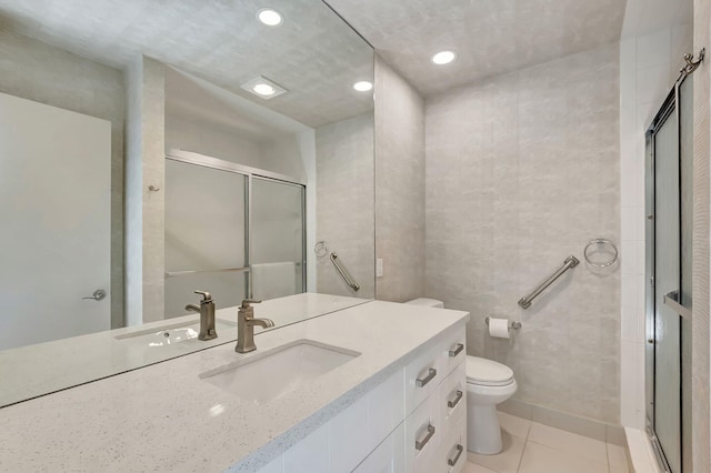 full bath with tile walls, toilet, a stall shower, vanity, and tile patterned floors