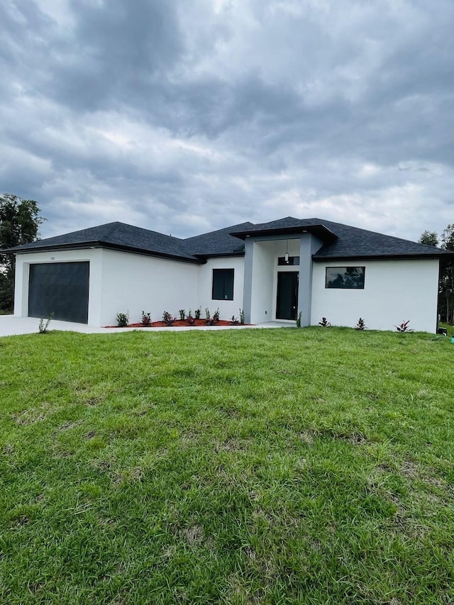 prairie-style home with a garage, a front yard, and stucco siding