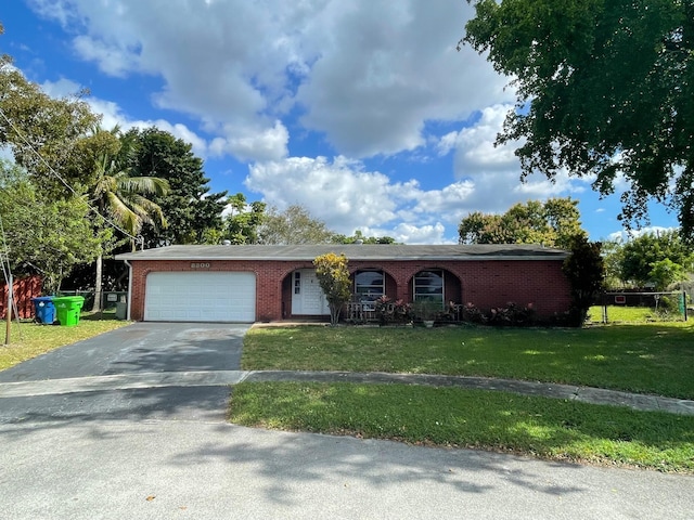 single story home featuring driveway, an attached garage, a front lawn, and brick siding