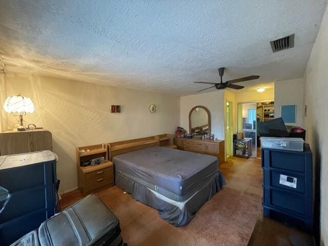 carpeted bedroom with ceiling fan, a closet, visible vents, and a textured ceiling