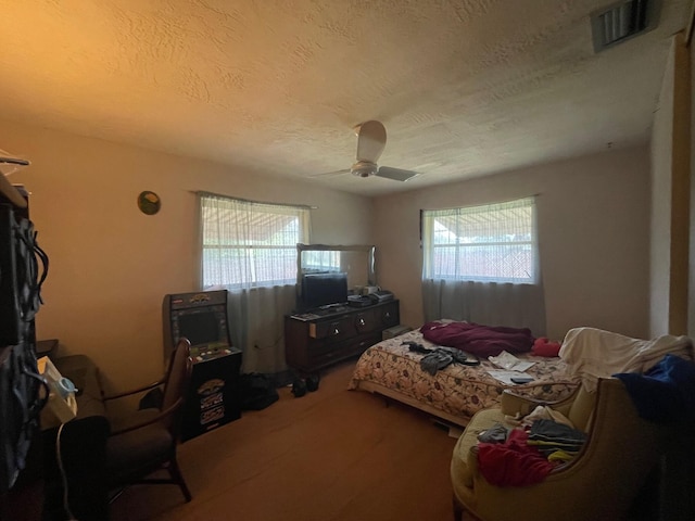 bedroom with a textured ceiling, ceiling fan, and visible vents