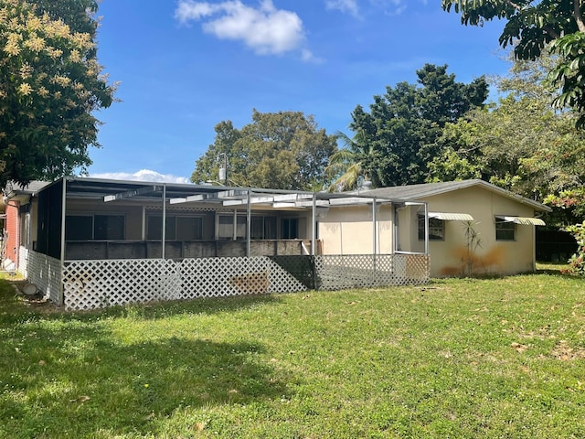 rear view of house with a sunroom and a yard