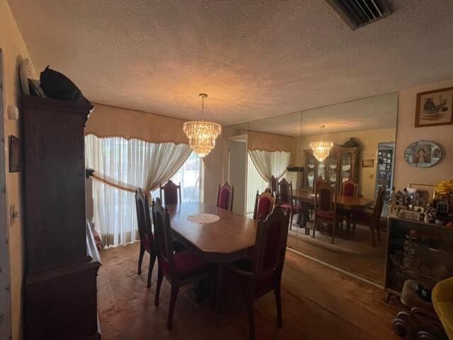 dining room featuring visible vents, a notable chandelier, and a textured ceiling