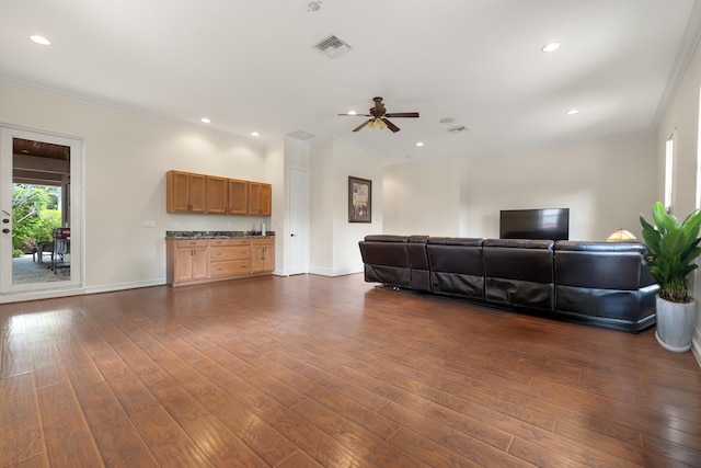 living area with visible vents, baseboards, dark wood-style floors, and crown molding