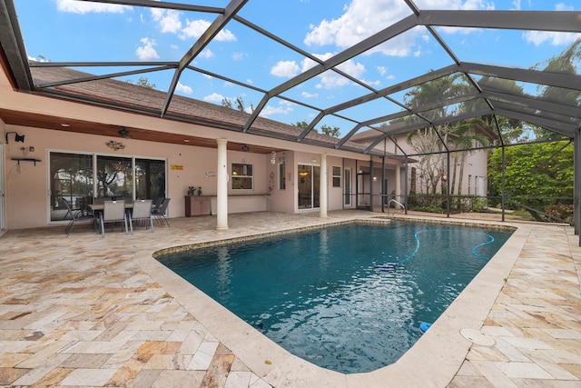 outdoor pool featuring glass enclosure and a patio