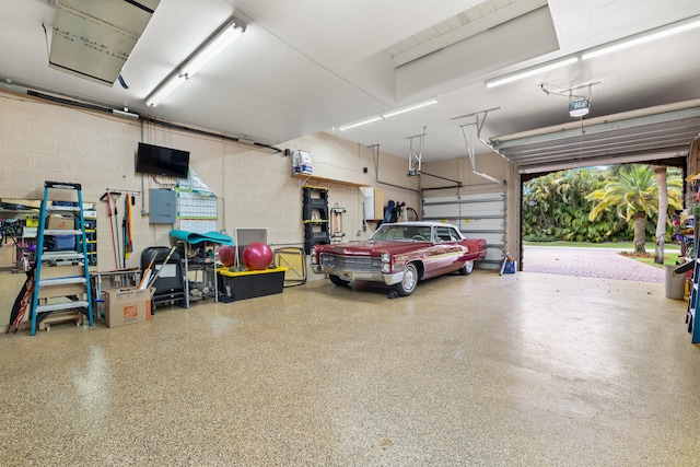 garage with concrete block wall, electric panel, and a garage door opener