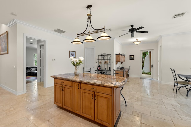 kitchen featuring stone tile flooring, visible vents, a kitchen island, and baseboards