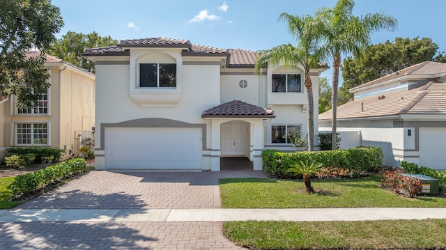 mediterranean / spanish house with a garage, decorative driveway, a tile roof, and stucco siding