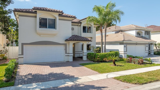 mediterranean / spanish house featuring a tiled roof, decorative driveway, and stucco siding