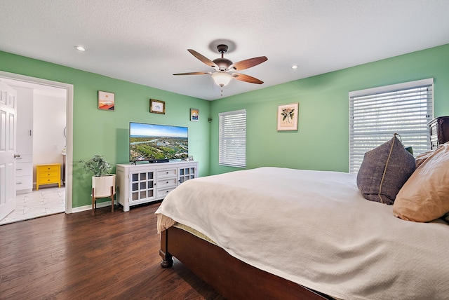 bedroom with a textured ceiling, multiple windows, baseboards, and wood finished floors