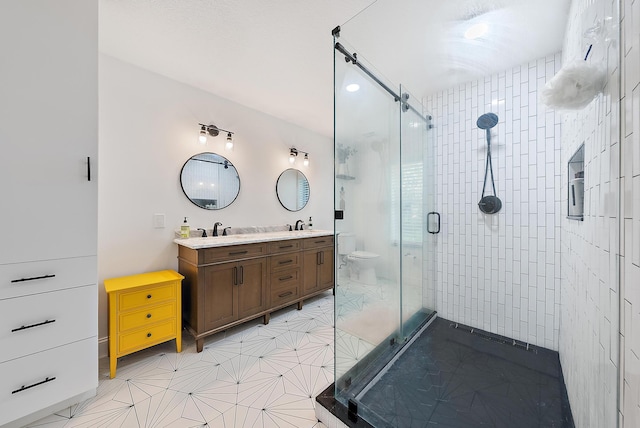 full bathroom with double vanity, a stall shower, a sink, and toilet