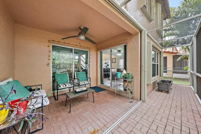 view of patio / terrace featuring ceiling fan and glass enclosure