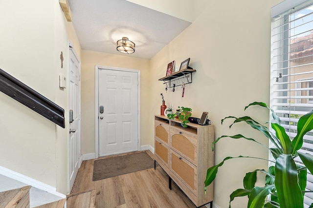 doorway with light wood-style flooring and baseboards