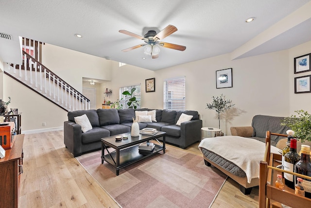 living area with light wood-style floors, stairway, a textured ceiling, and a ceiling fan