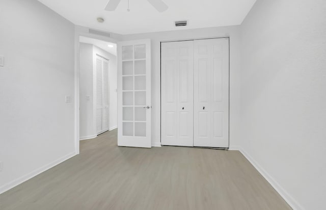 unfurnished bedroom with baseboards, a closet, visible vents, and wood finished floors