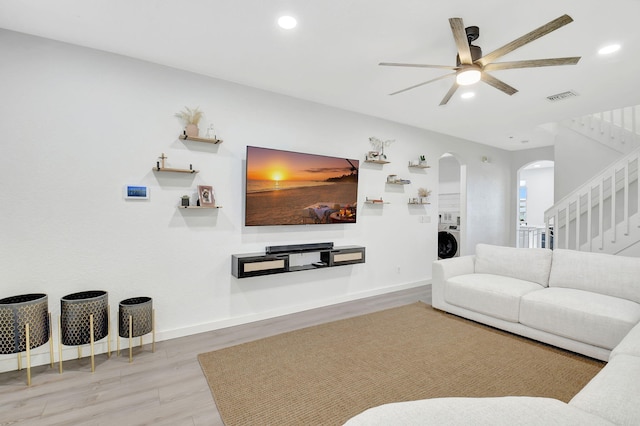 living room featuring baseboards, visible vents, arched walkways, washer / clothes dryer, and wood finished floors