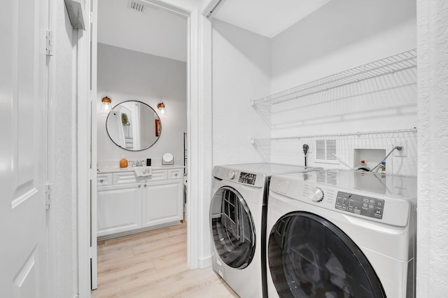 laundry area featuring laundry area, washer and clothes dryer, light wood-type flooring, and visible vents