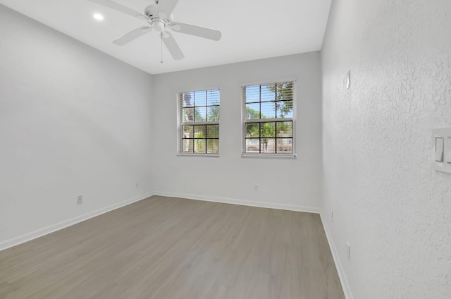 unfurnished room featuring ceiling fan, a textured wall, wood finished floors, and baseboards