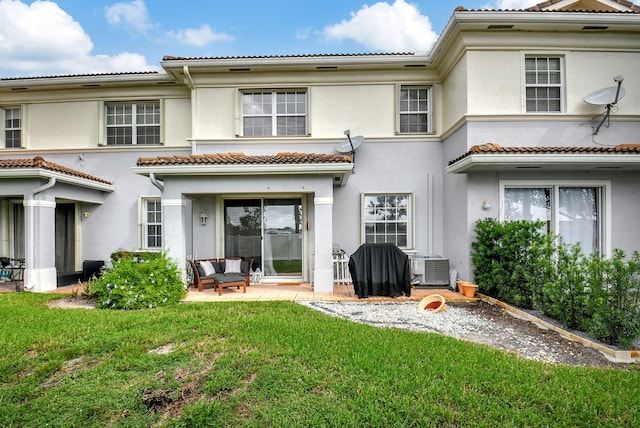 rear view of property with central air condition unit, a tile roof, a yard, stucco siding, and a patio area