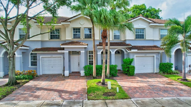 view of front of home featuring a garage, decorative driveway, a tile roof, and stucco siding