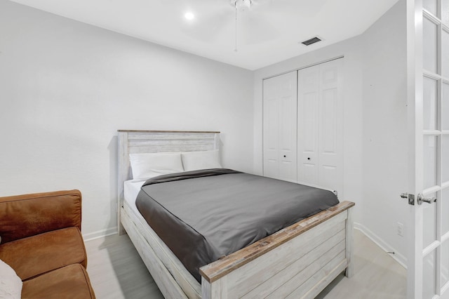 bedroom featuring ceiling fan, light wood-style flooring, visible vents, baseboards, and a closet