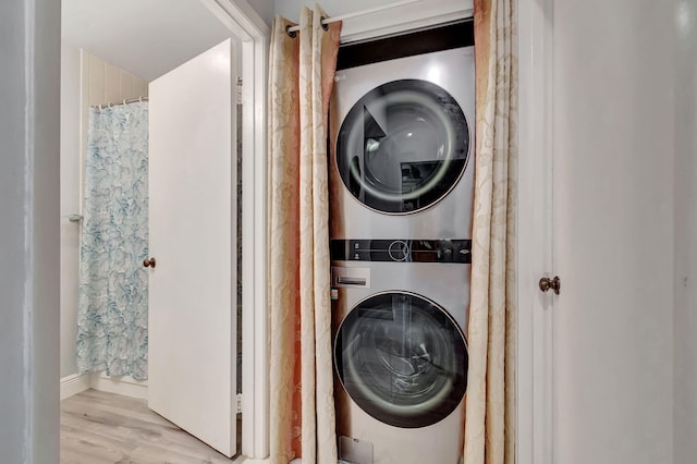 laundry area featuring stacked washing maching and dryer, laundry area, and wood finished floors