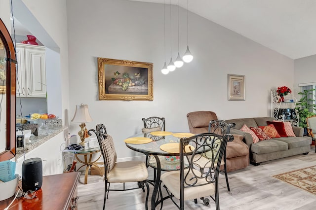 dining room featuring light wood-style floors and high vaulted ceiling