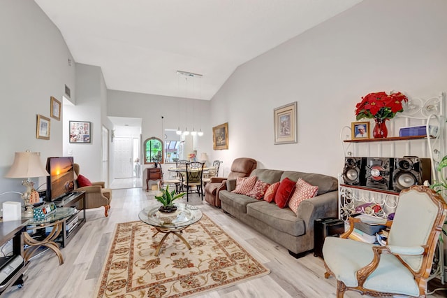 living area with high vaulted ceiling, light wood-type flooring, and visible vents