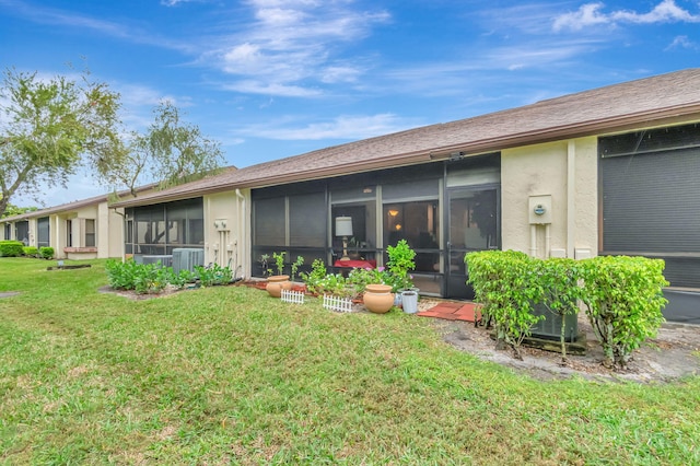 rear view of property with a sunroom, cooling unit, a lawn, and stucco siding