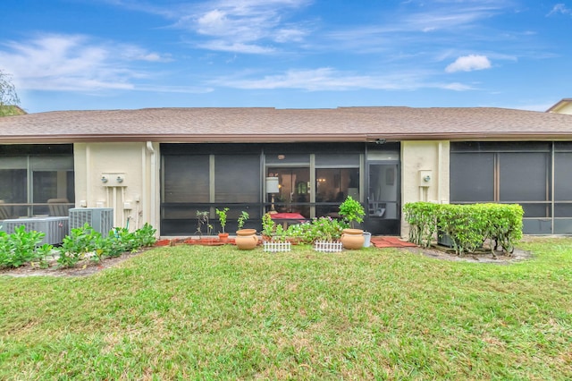 rear view of house featuring cooling unit, a sunroom, a lawn, and stucco siding