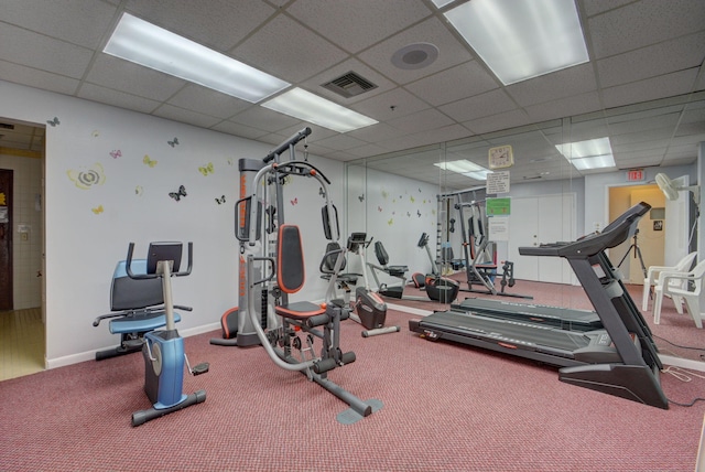 workout area with baseboards, visible vents, and a drop ceiling