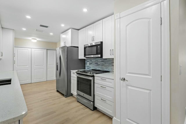 kitchen featuring white cabinets, appliances with stainless steel finishes, light wood-style floors, backsplash, and recessed lighting