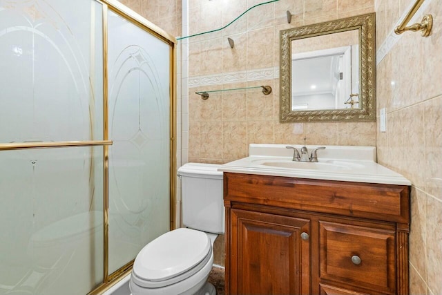 bathroom with toilet, a shower stall, tile walls, and vanity