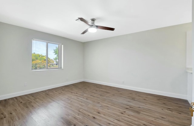 empty room featuring a ceiling fan, baseboards, and wood finished floors