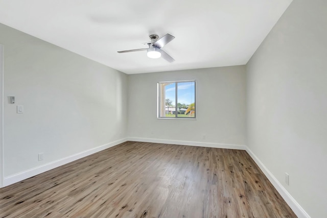 spare room featuring ceiling fan, baseboards, and wood finished floors