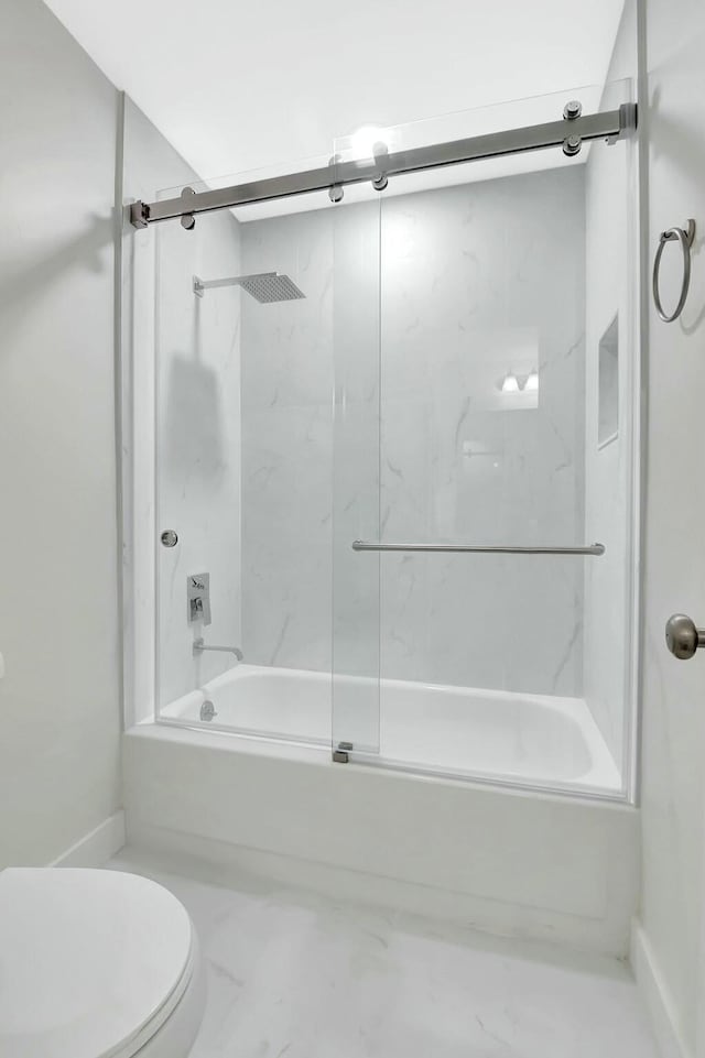 bathroom featuring toilet, marble finish floor, and combined bath / shower with glass door