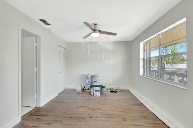 spare room with ceiling fan, wood finished floors, visible vents, and baseboards