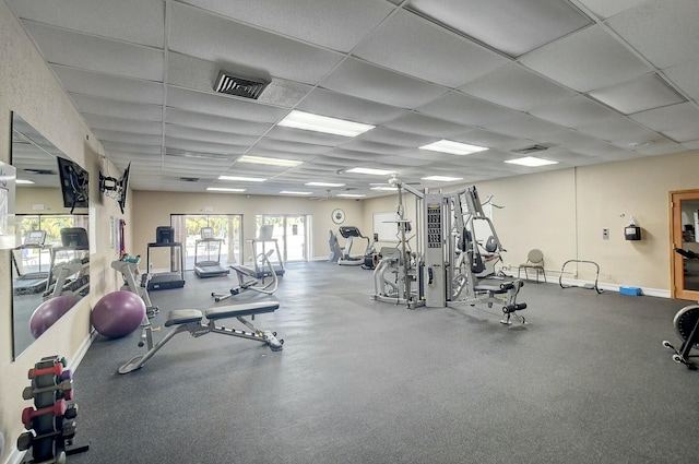 workout area featuring visible vents, a paneled ceiling, and baseboards