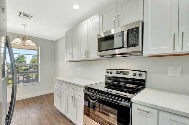 kitchen with visible vents, stainless steel microwave, white cabinets, and electric stove