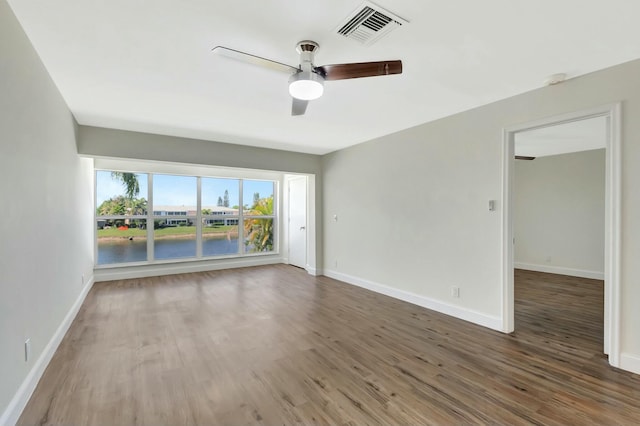 spare room featuring visible vents, ceiling fan, baseboards, and wood finished floors