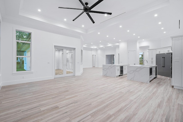 kitchen featuring a tray ceiling, open floor plan, a large island with sink, and a sink