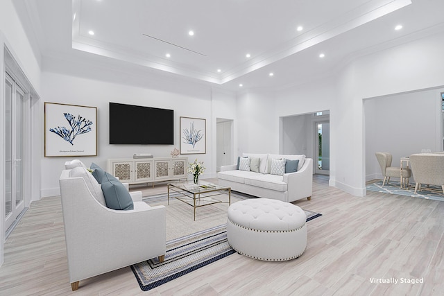 living area with a raised ceiling, light wood-style flooring, a high ceiling, crown molding, and recessed lighting