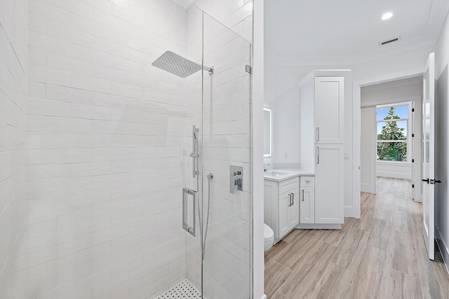 full bath with recessed lighting, wood finished floors, vanity, a shower stall, and crown molding