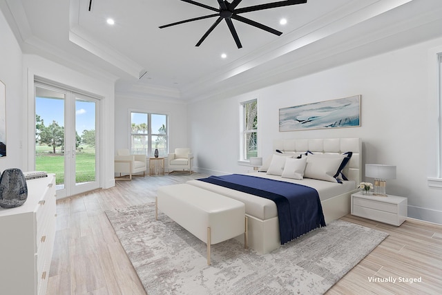 bedroom featuring ornamental molding, french doors, a raised ceiling, and light wood-style flooring