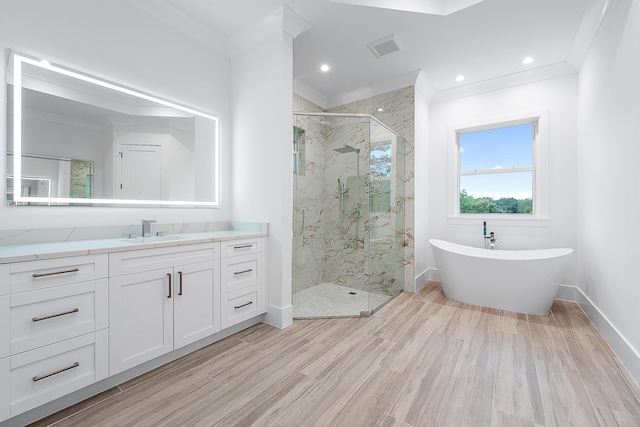 bathroom with vanity, visible vents, a freestanding bath, a marble finish shower, and crown molding