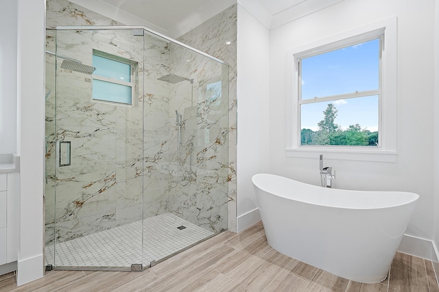 full bathroom featuring wood finish floors, a soaking tub, a marble finish shower, and baseboards