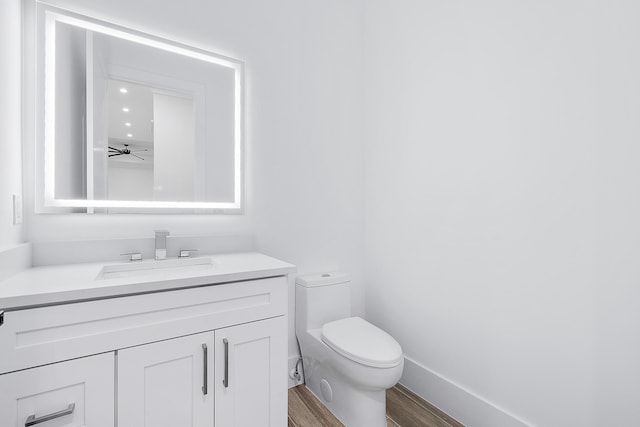 bathroom featuring vanity, wood finished floors, toilet, and baseboards