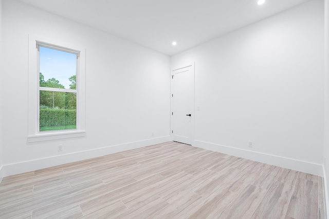 spare room featuring recessed lighting, light wood finished floors, and baseboards